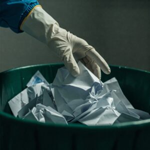 Discarded bank statements and mail visible in an unsecured trash bin, illustrating the risk of identity theft through dumpster diving.