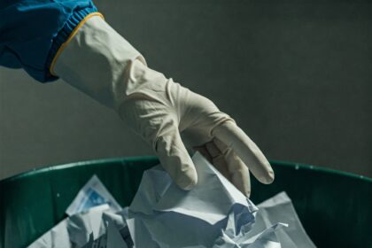 Discarded bank statements and mail visible in an unsecured trash bin, illustrating the risk of identity theft through dumpster diving.