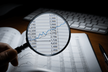A magnifying glass focusing on a financial ledger, illustrating the importance of internal controls and vigilant oversight for preventing employee wire fraud in small businesses.